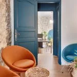 Espace café de l'agence immobilière avec fauteuils velours orange et bleu et table basse en rotin, par Kty.L Décoratrice d'intérieur, UFDI, Vaucluse et Gard